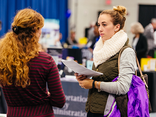 female student talks with company representative at a career fair