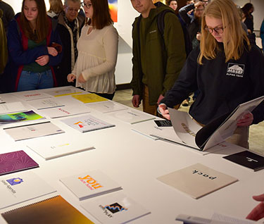 Champlain College students checking out the graphic design work of senior Visual Communication Design major students.