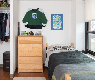 Typical bedroom with twin bed, dresser, and closet in a contemporary residence hall. 