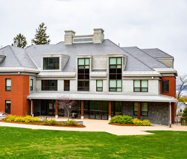 View of the front of Butler Hall, a contemporary residence hall, with a view of Lake Champlain in the distance behind it.