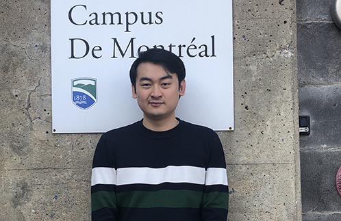 Champlain student Raymond Zheng stands in front of the Champlain College Montreal Campus sign