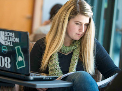 female student studies with laptop and textbook