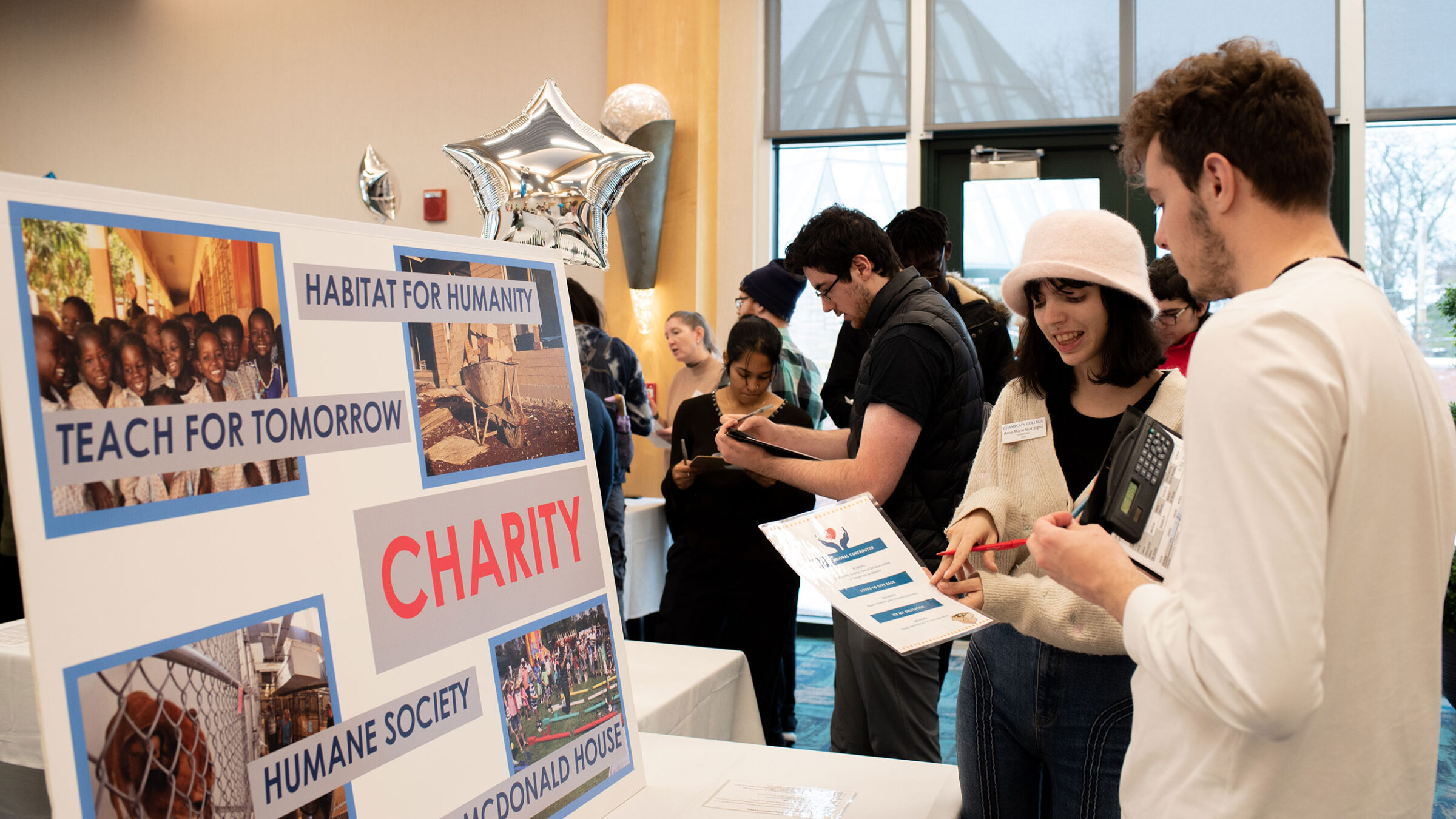 Two people collaborate in front of a sign about different kinds of charities to donate to.
