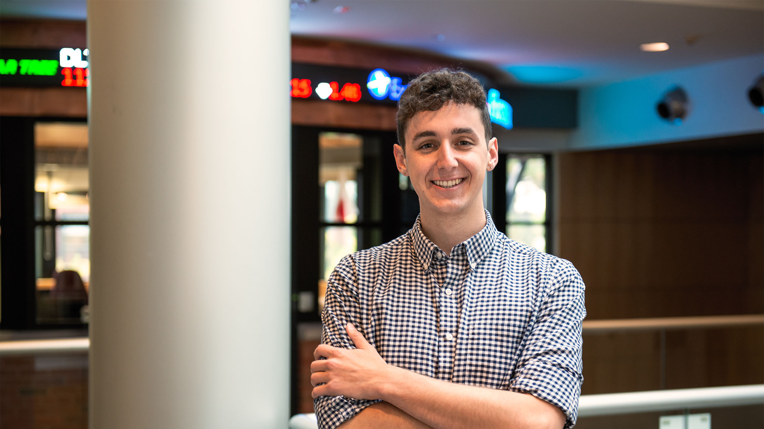 student stand in front of classroom with stock market ticker moving along the top