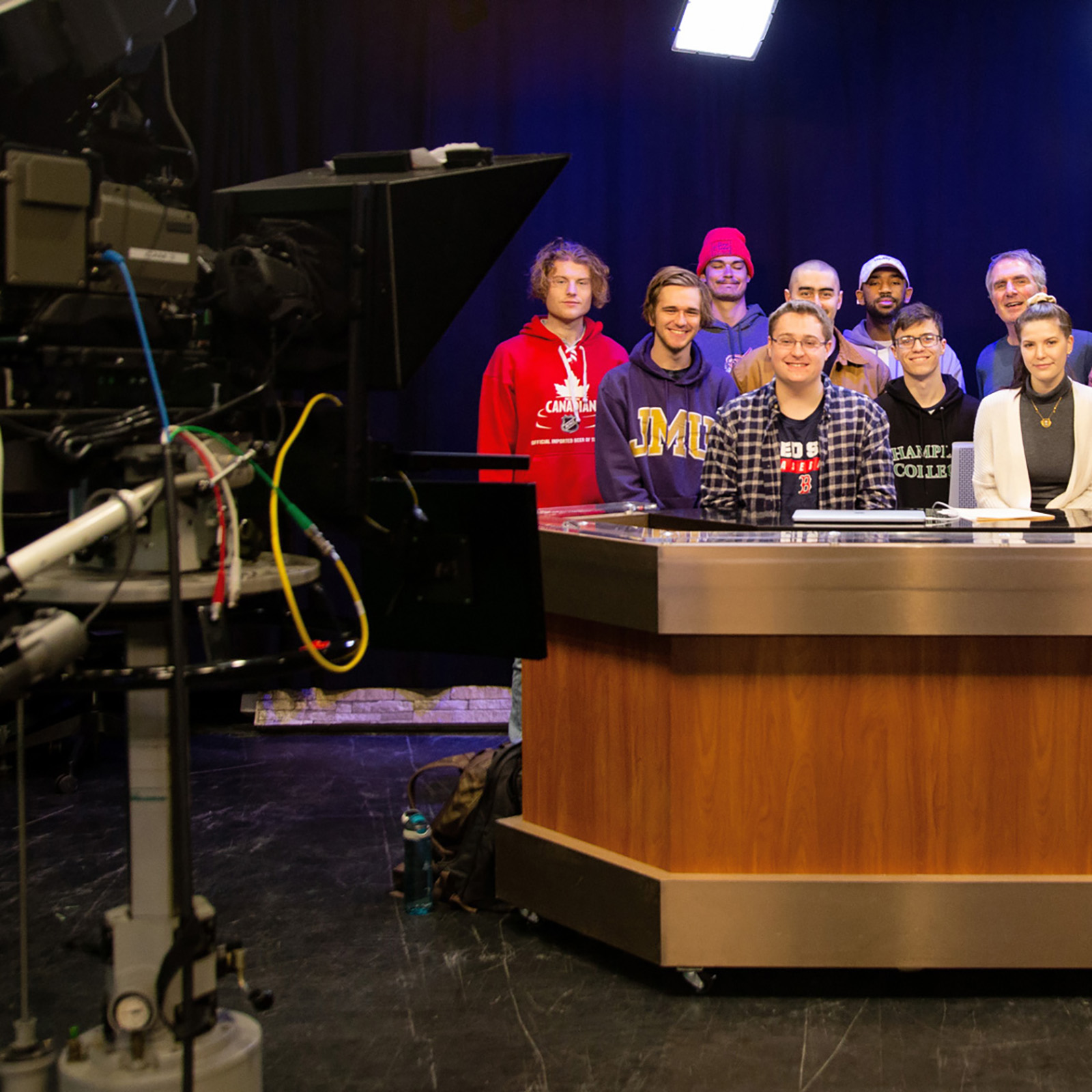 groups of students at news desk, broadcast camera in the foreground
