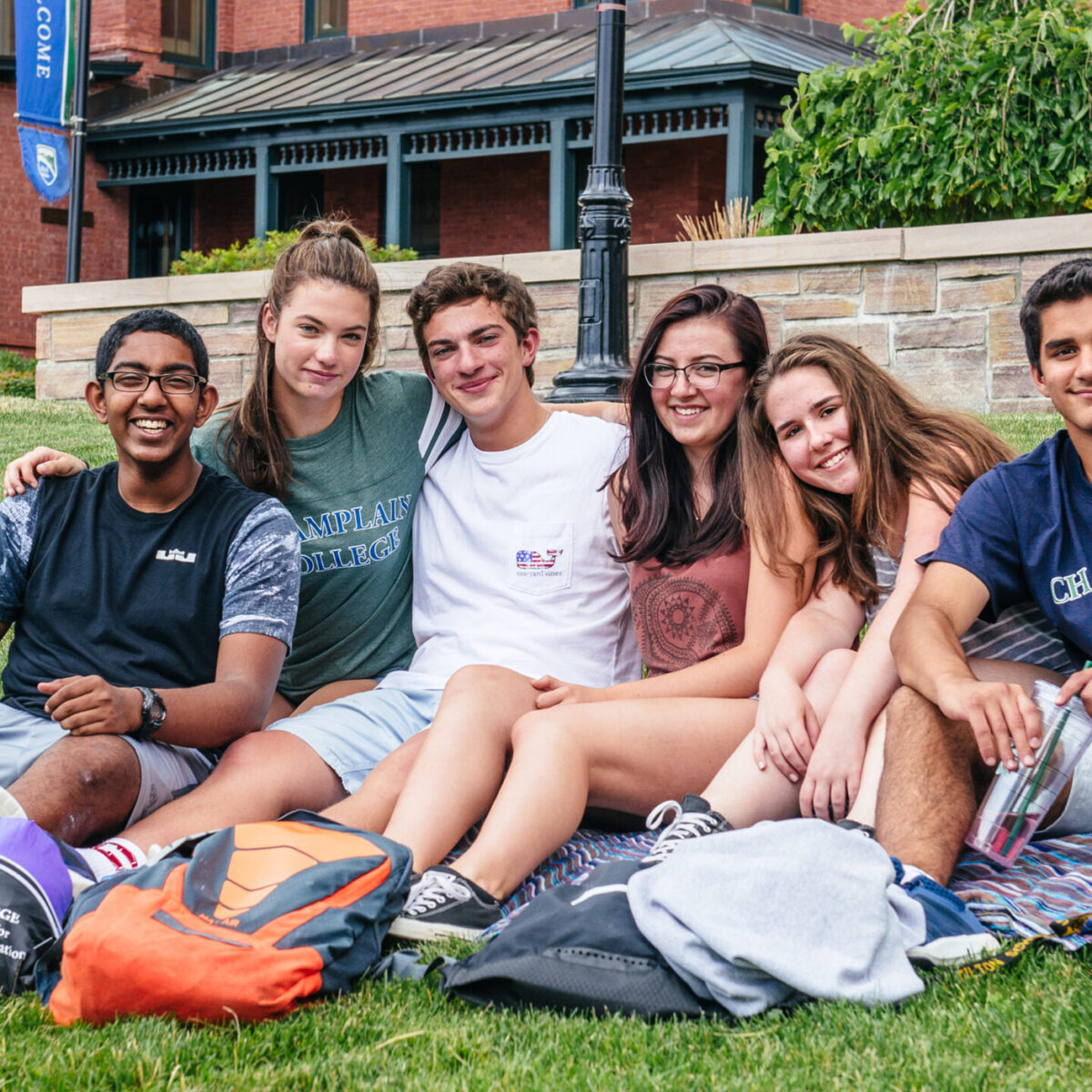 group of students sit on a blanket on the lawn