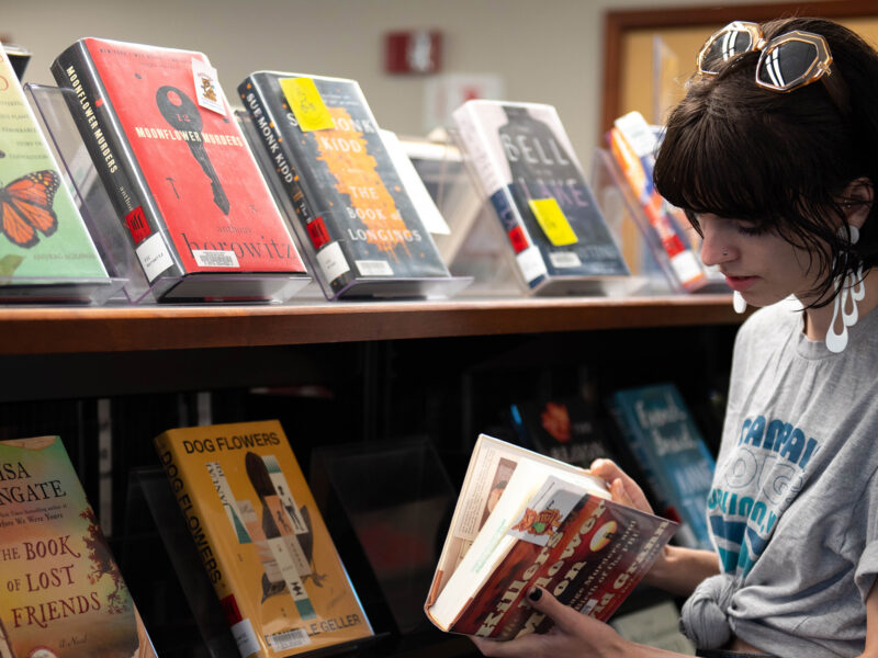 student chooses book from the library shelf