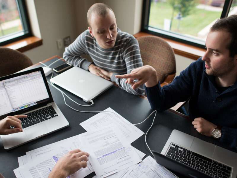 Three students working together around a table in a library study room