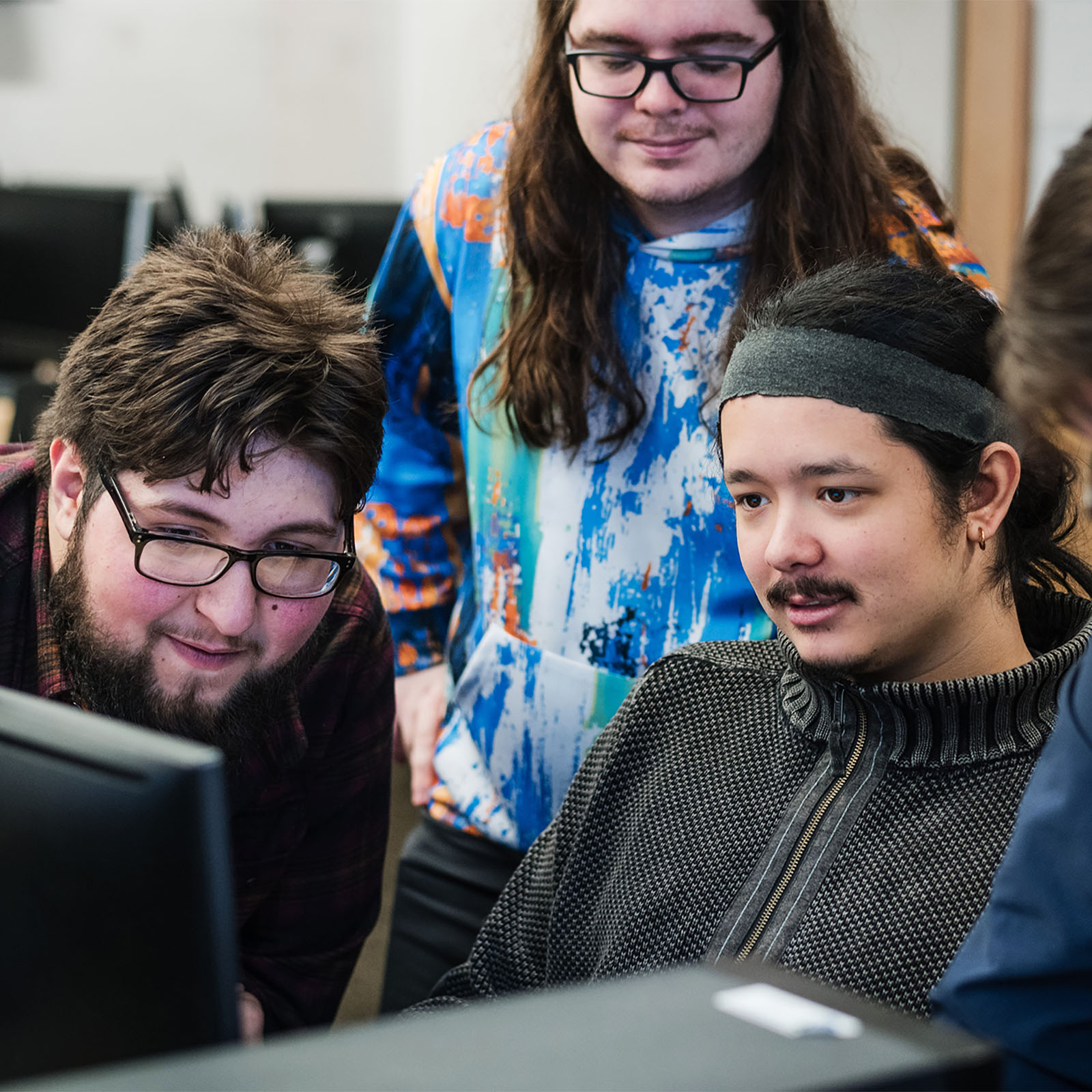 A group of Game Business students collaborating over a computer
