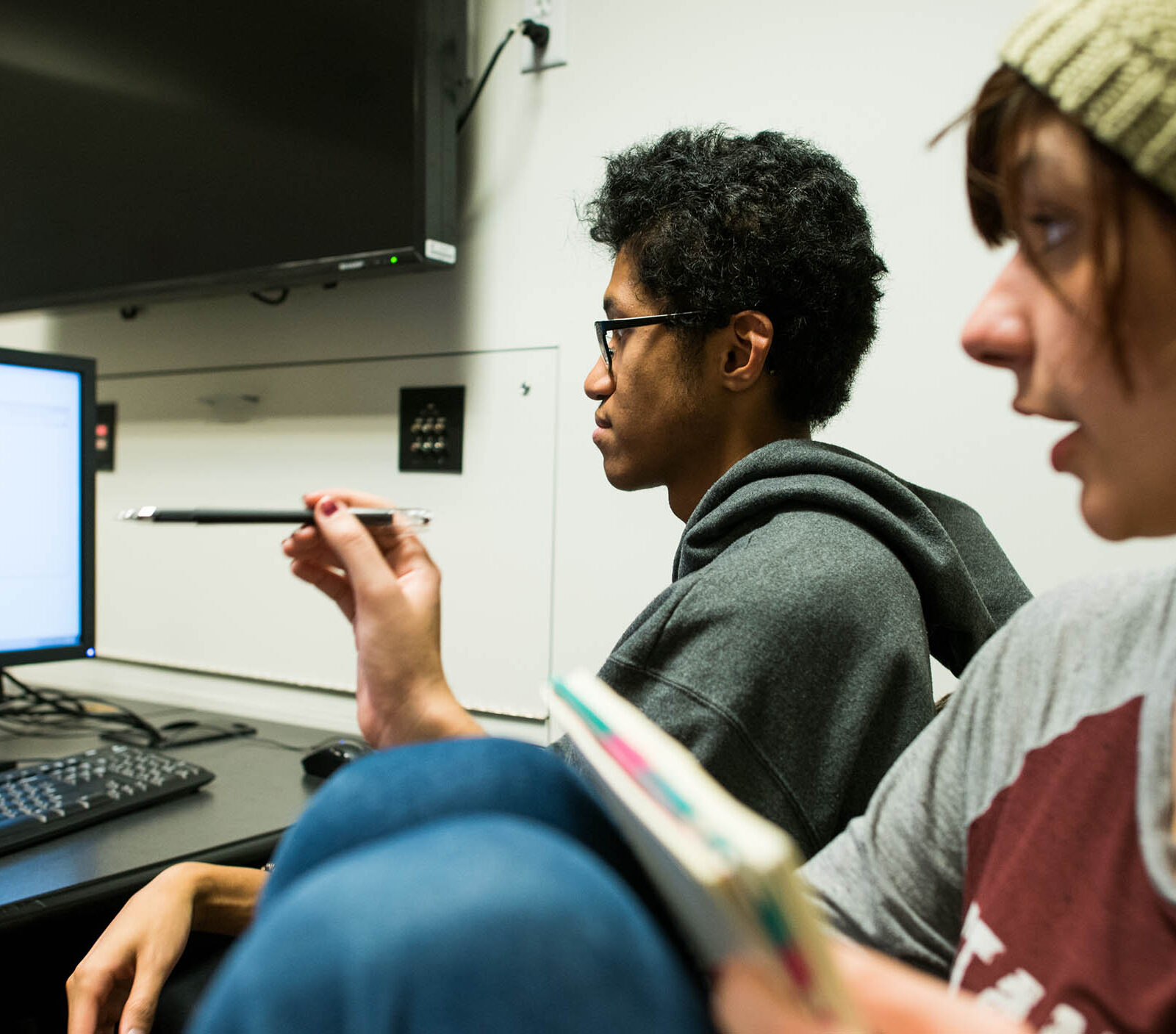 two students collaborating on a game design project in front of a computer screen