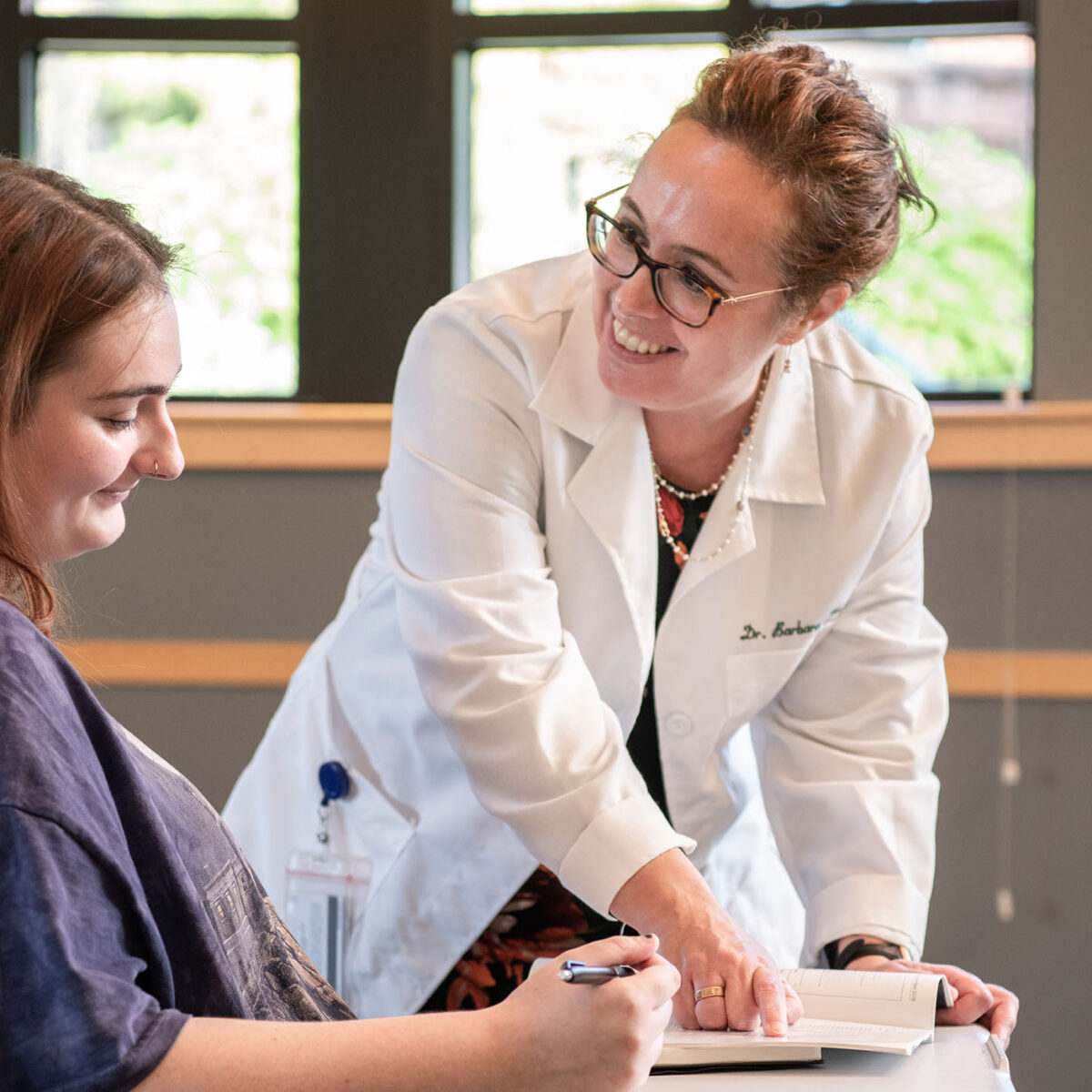 professor and student smiling while working on psychology classwork together