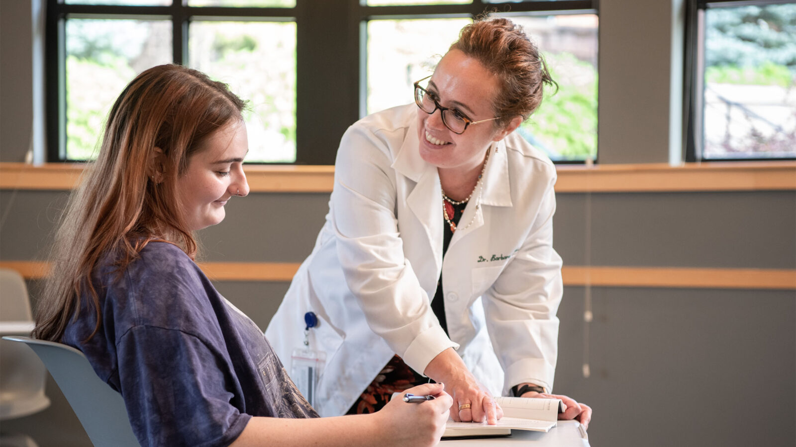 professor and student smiling while working on psychology classwork together