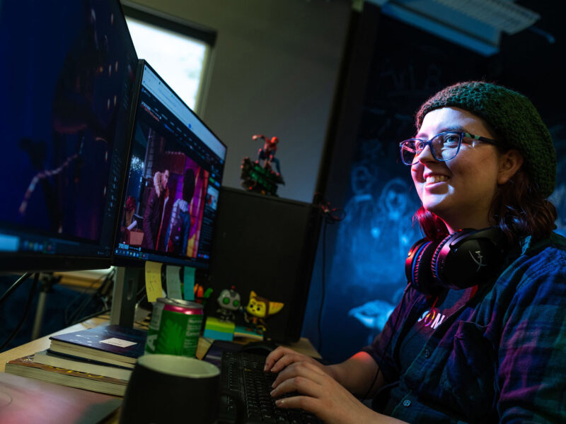 Game art student smiling at screen while working on a project