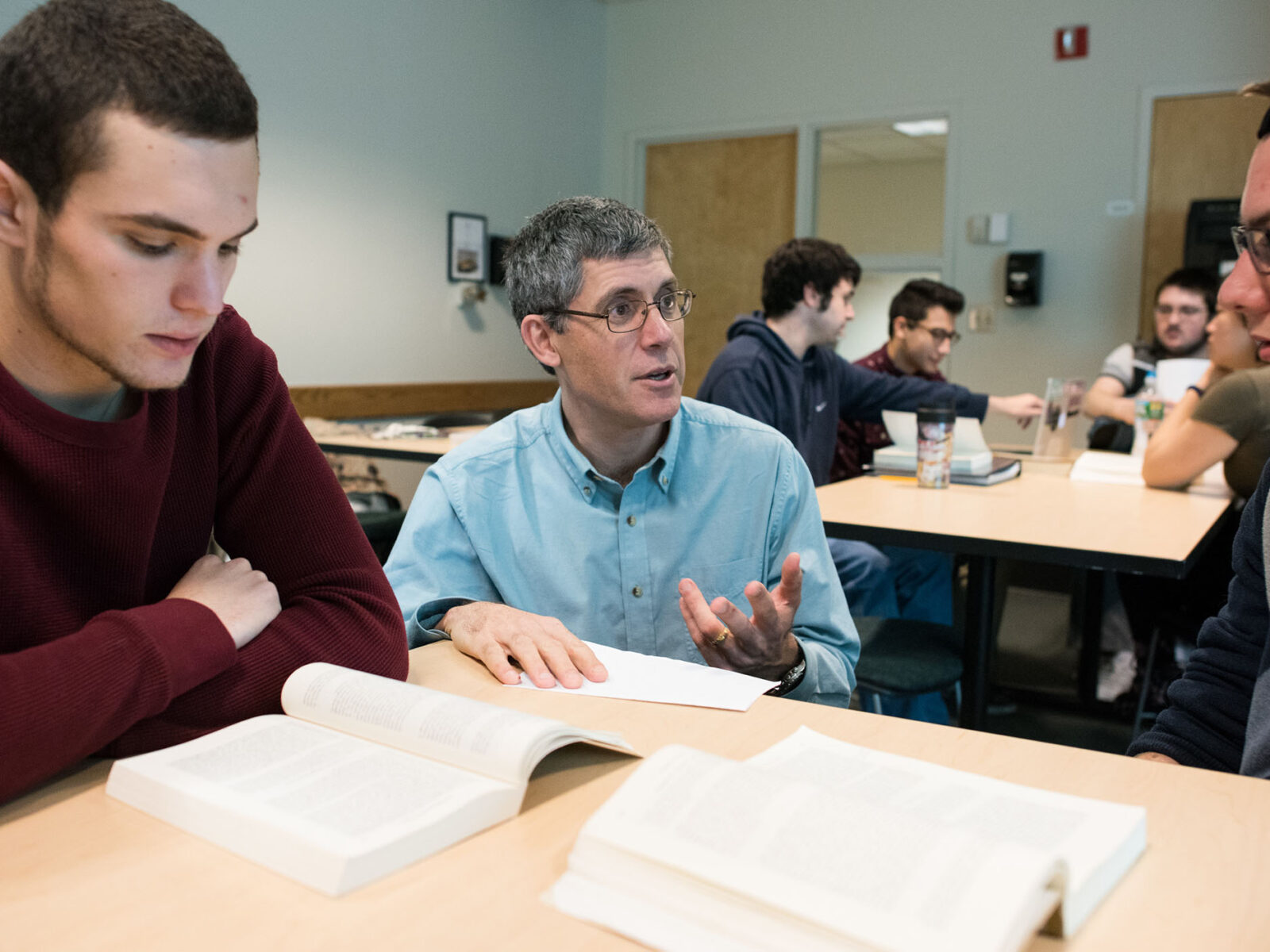 professor assisting two students with their reading assignment