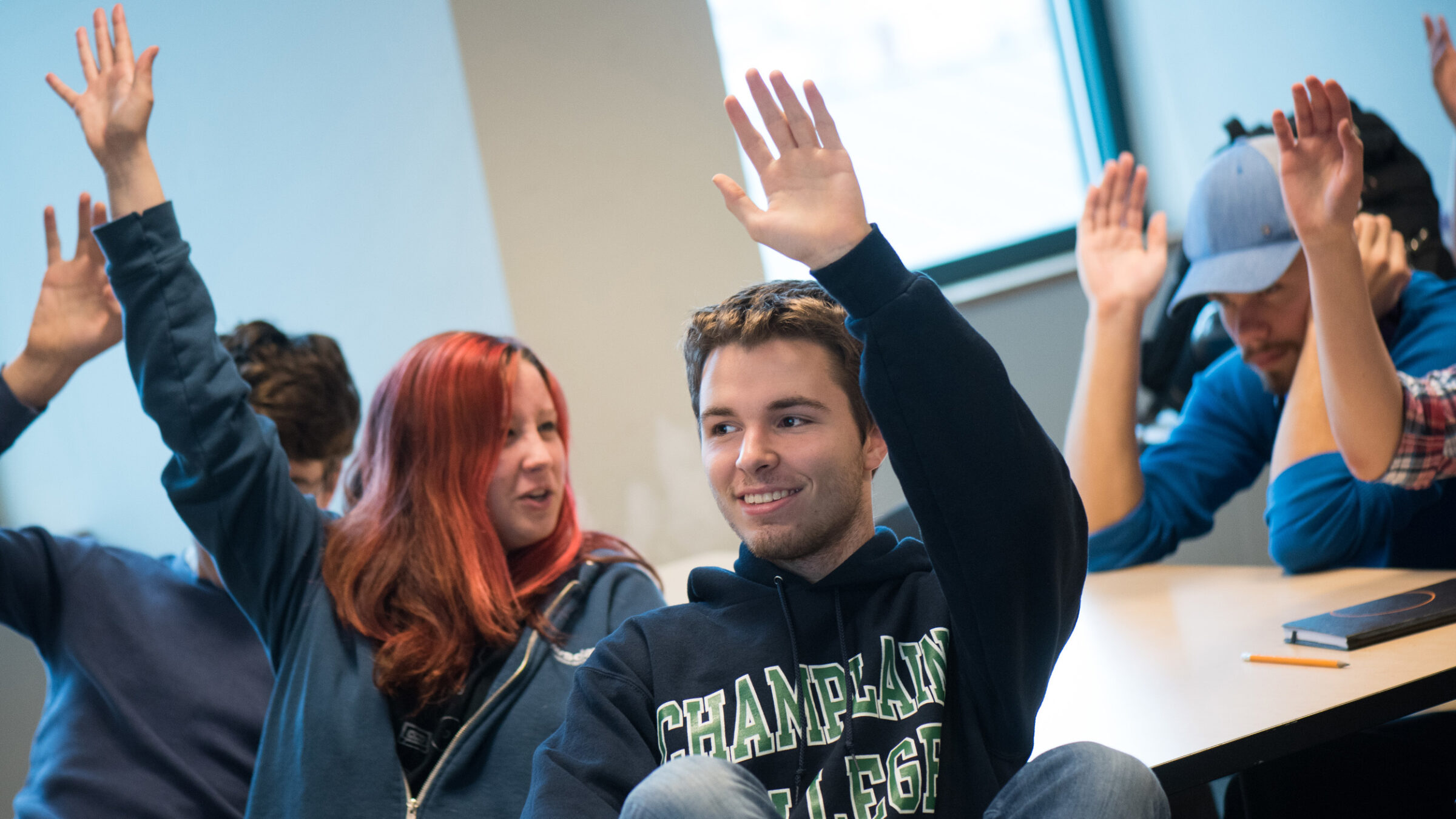 students raising their hands in class