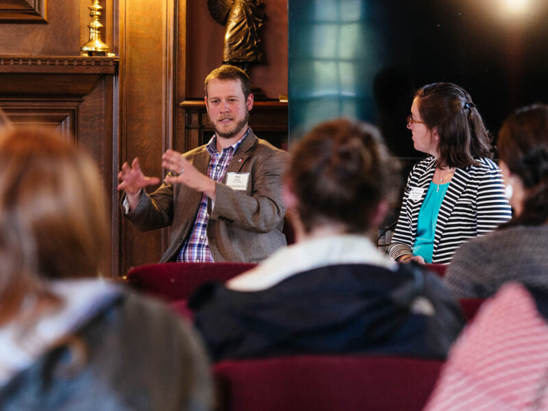 seated speakers talk to a group of conference attendees