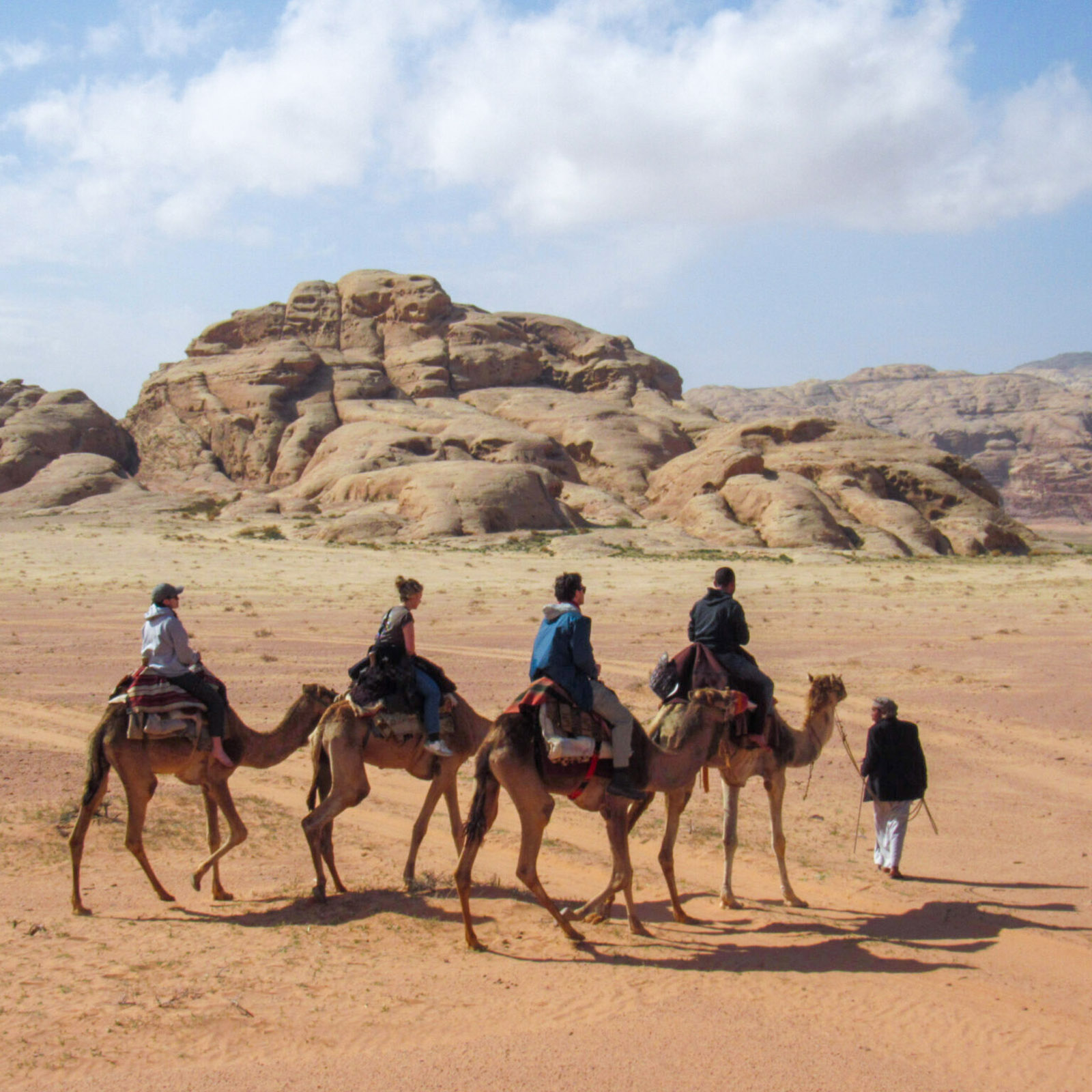 people riding camels in the Jordan desert