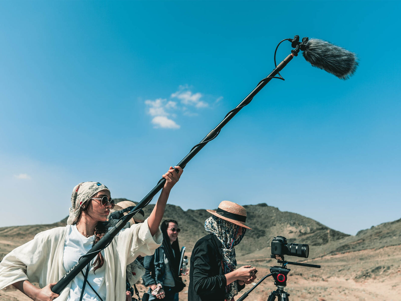 students filming in a desert using a camera and boom mic