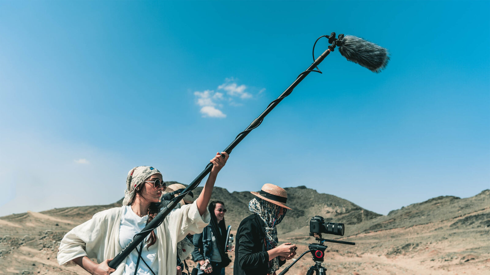 students filming in a desert using a camera and boom mic