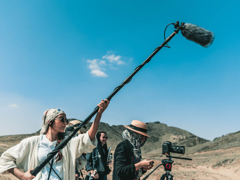 students filming in a desert using a camera and boom mic