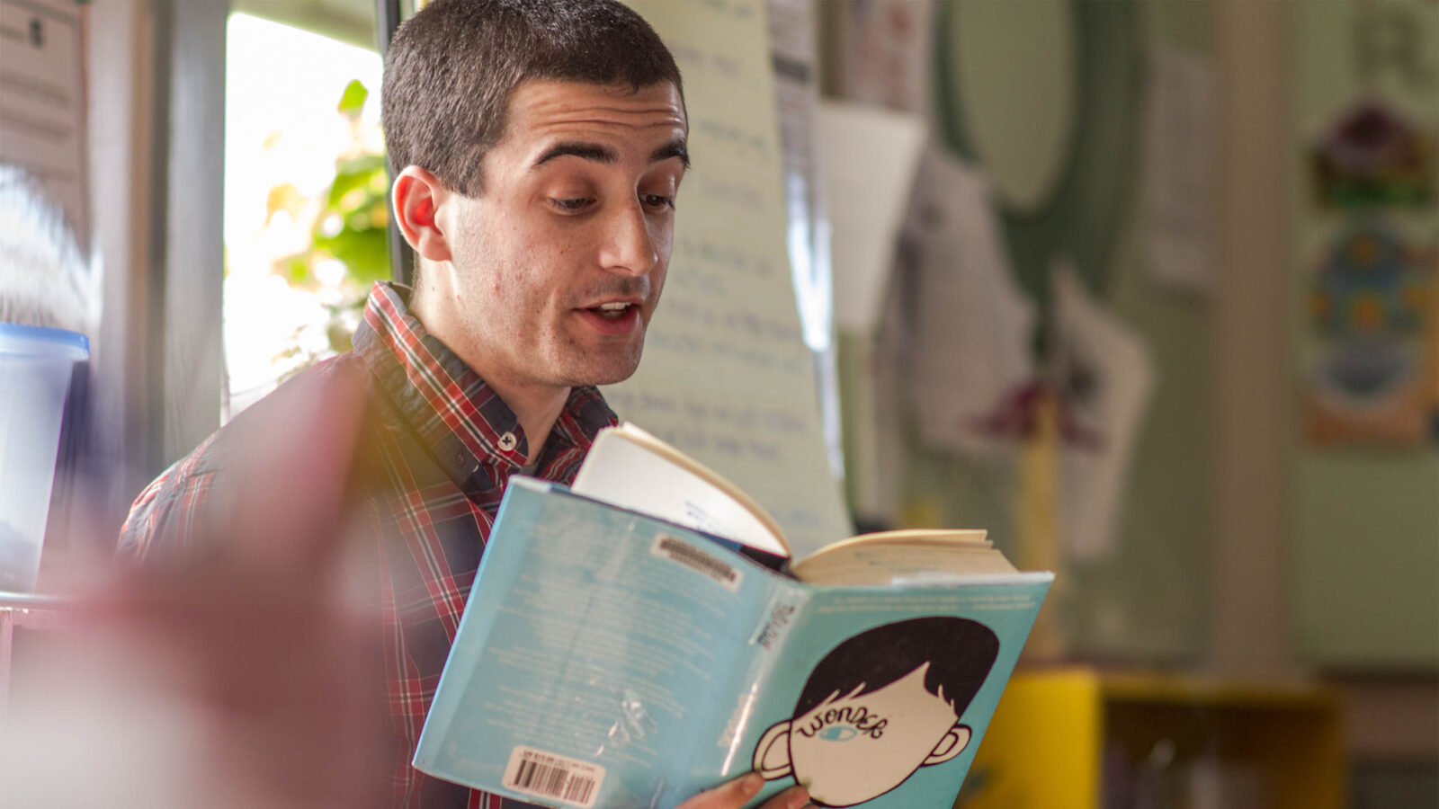 an education student reading a children's book in a classroom; student teaching