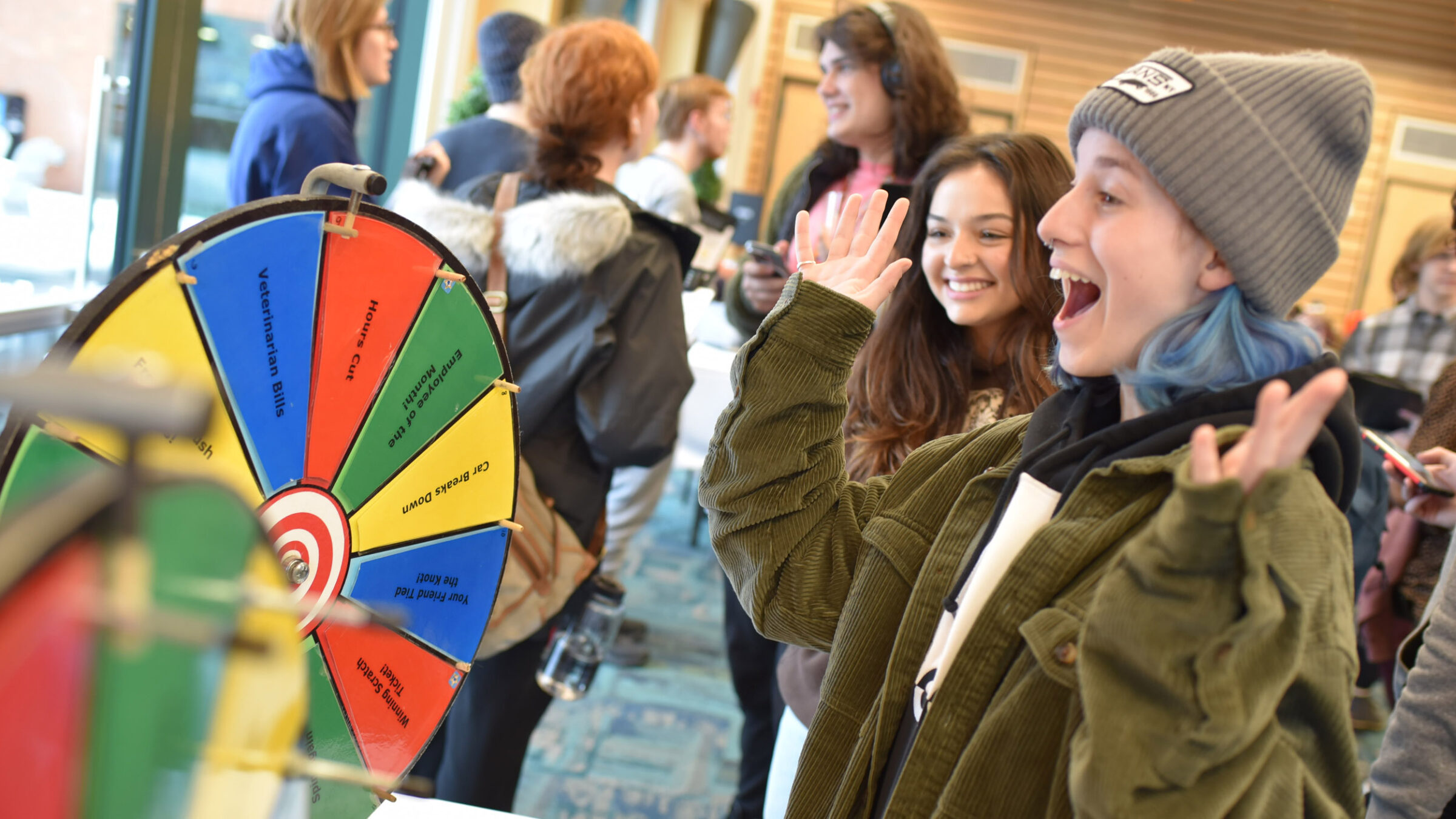 A student in front of a spin-the-wheel game looking very excited