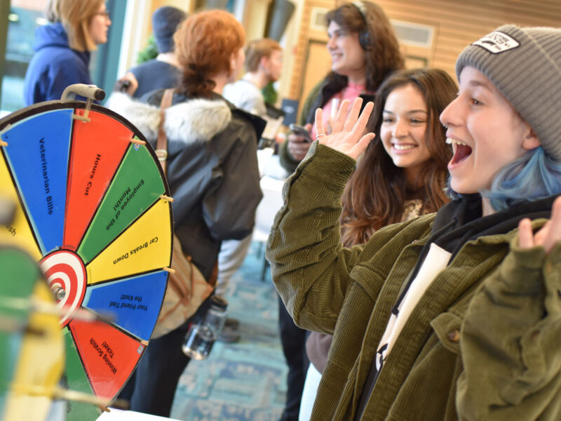 A student in front of a spin-the-wheel game looking very excited