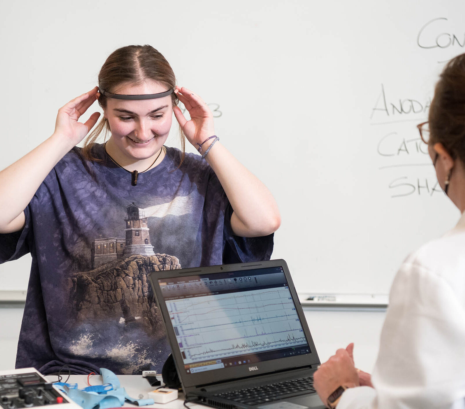psychology student and professor using brain scanner and getting data on a laptop