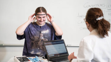 psychology student and professor using brain scanner and getting data on a laptop