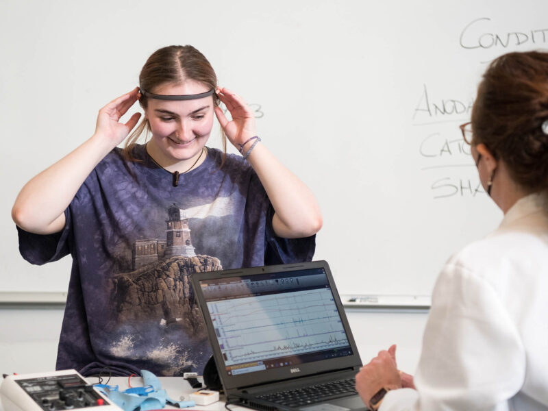 psychology student and professor using brain scanner and getting data on a laptop