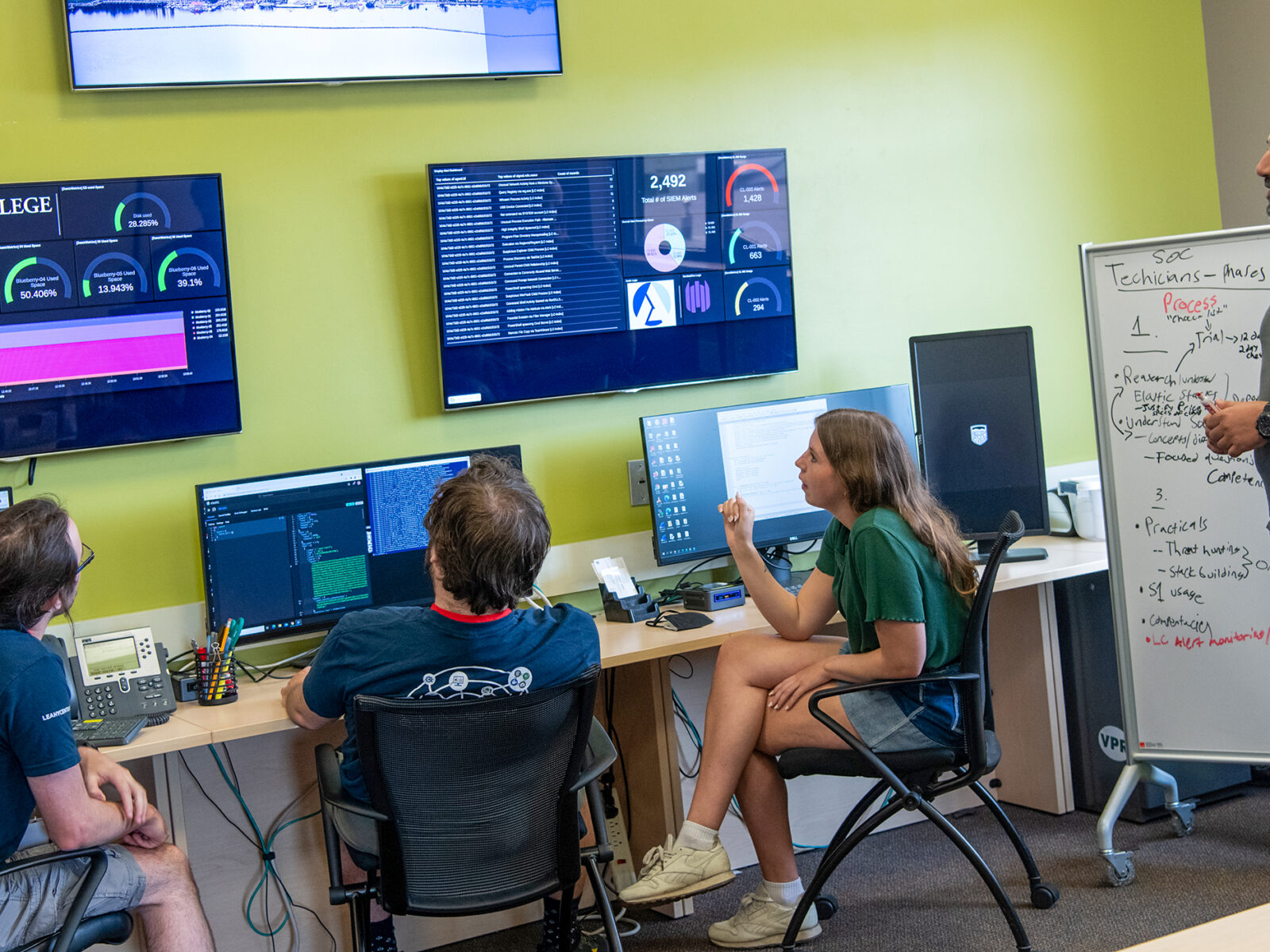 students and professor consider information on large screens