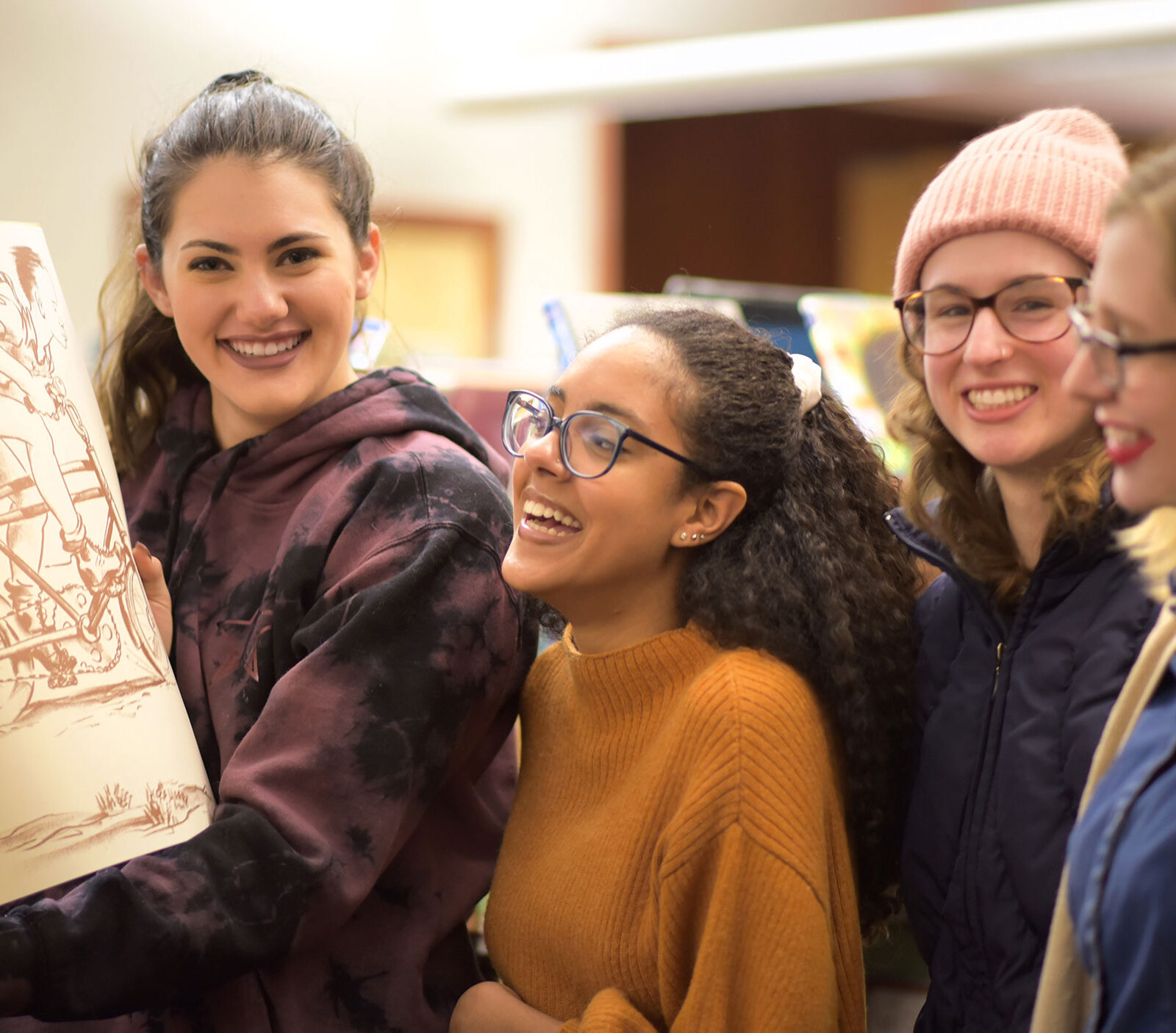 Four students look at an illustration book in the library