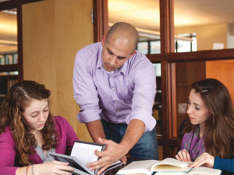 professor assisting two students with their reading