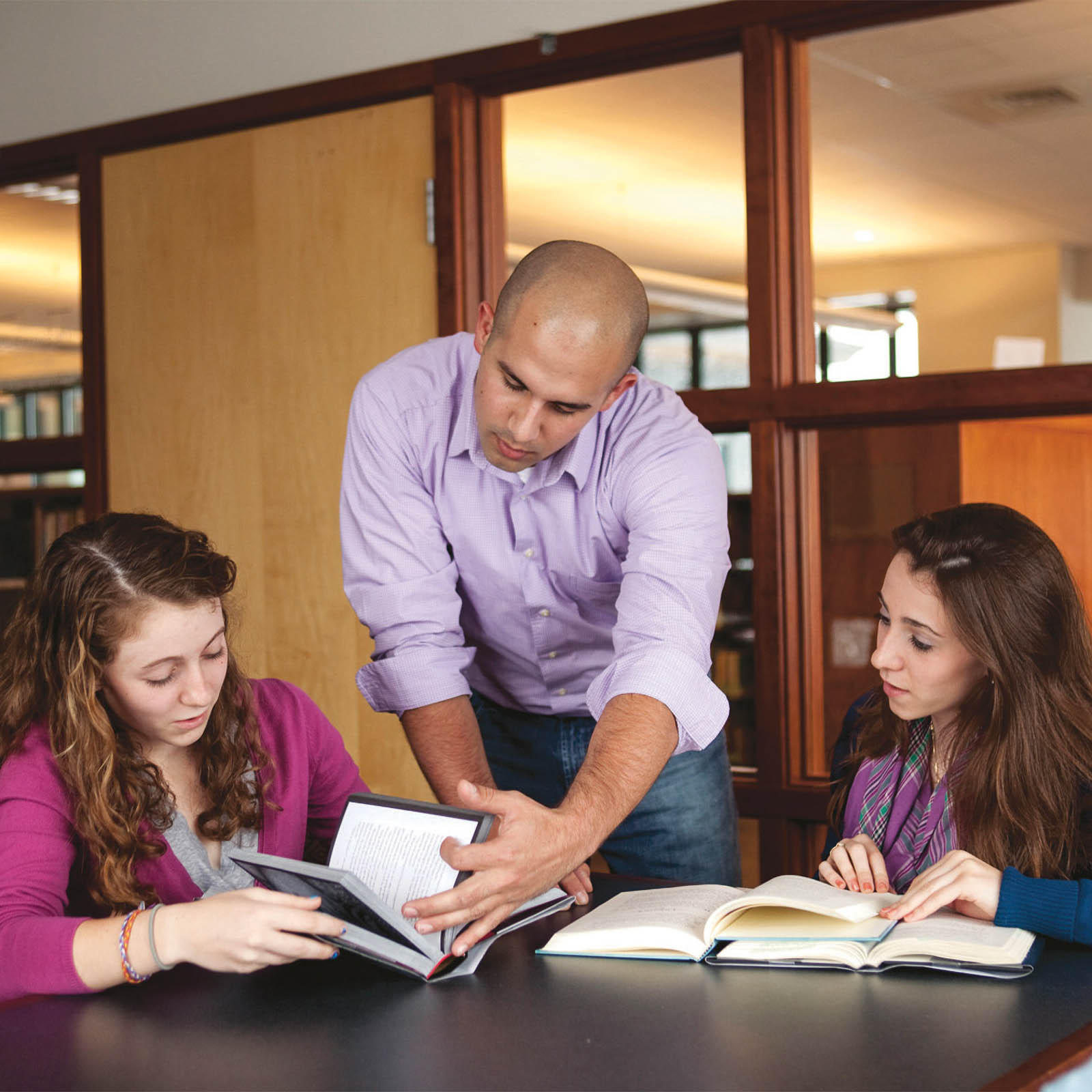 professor assisting two students with their reading