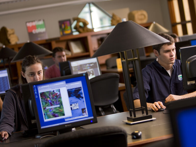 students at desktop computers study in the library