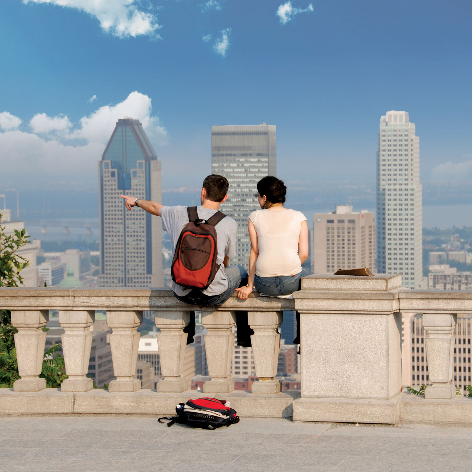 two abroad students sitting on a stone wall, overlooking the city in Mount Royal Park, Montreal
