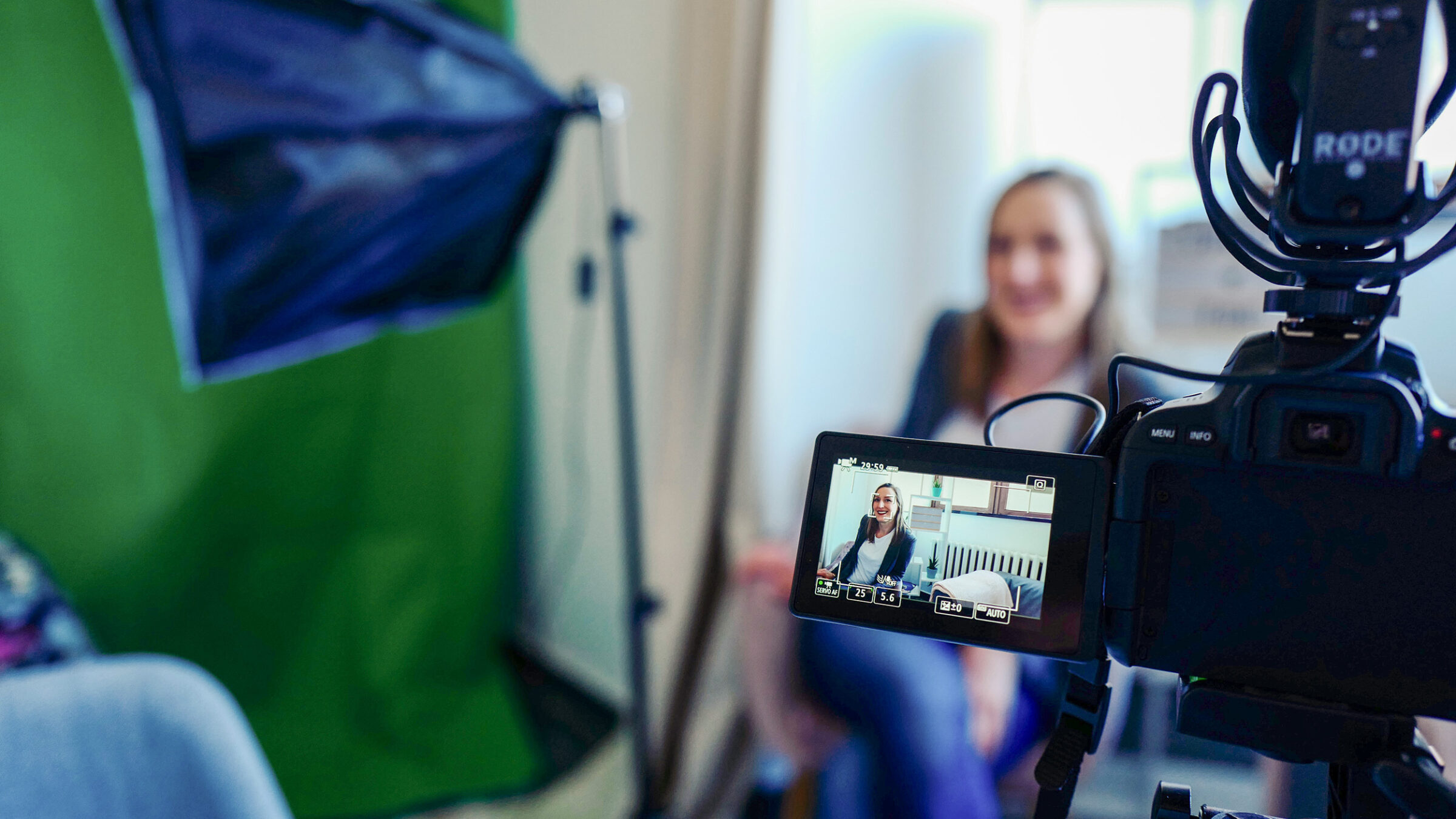 a woman being filmed in the background, the camera in the foreground