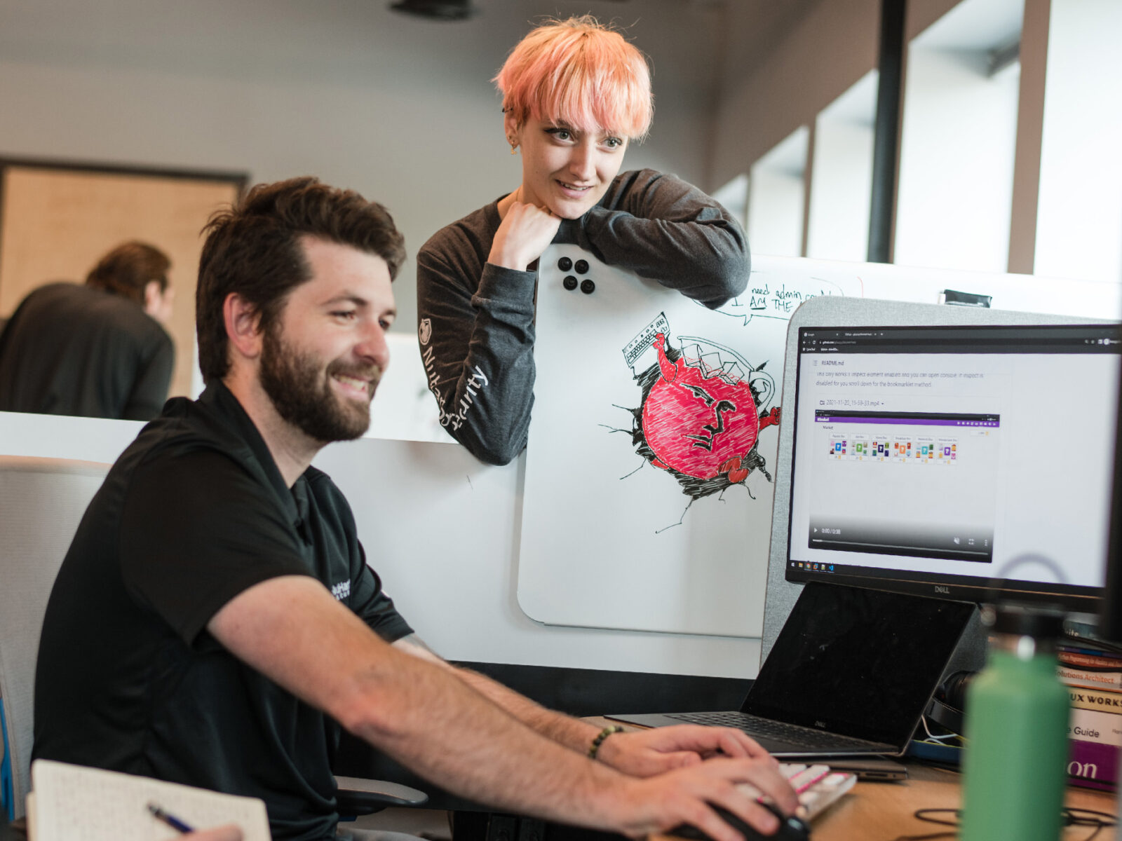 woman looks over the cubicle wall to take part in a discussion at a computer