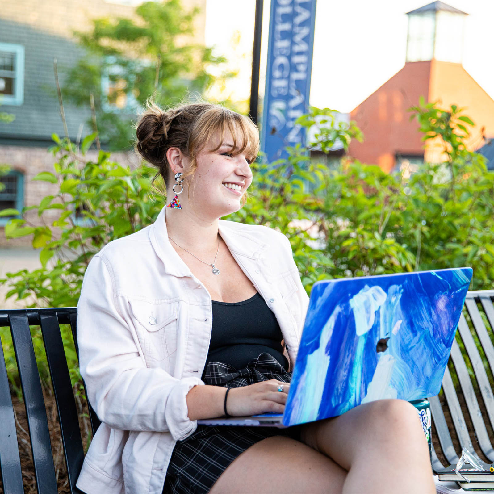 student smiles while using her laptop outdoors