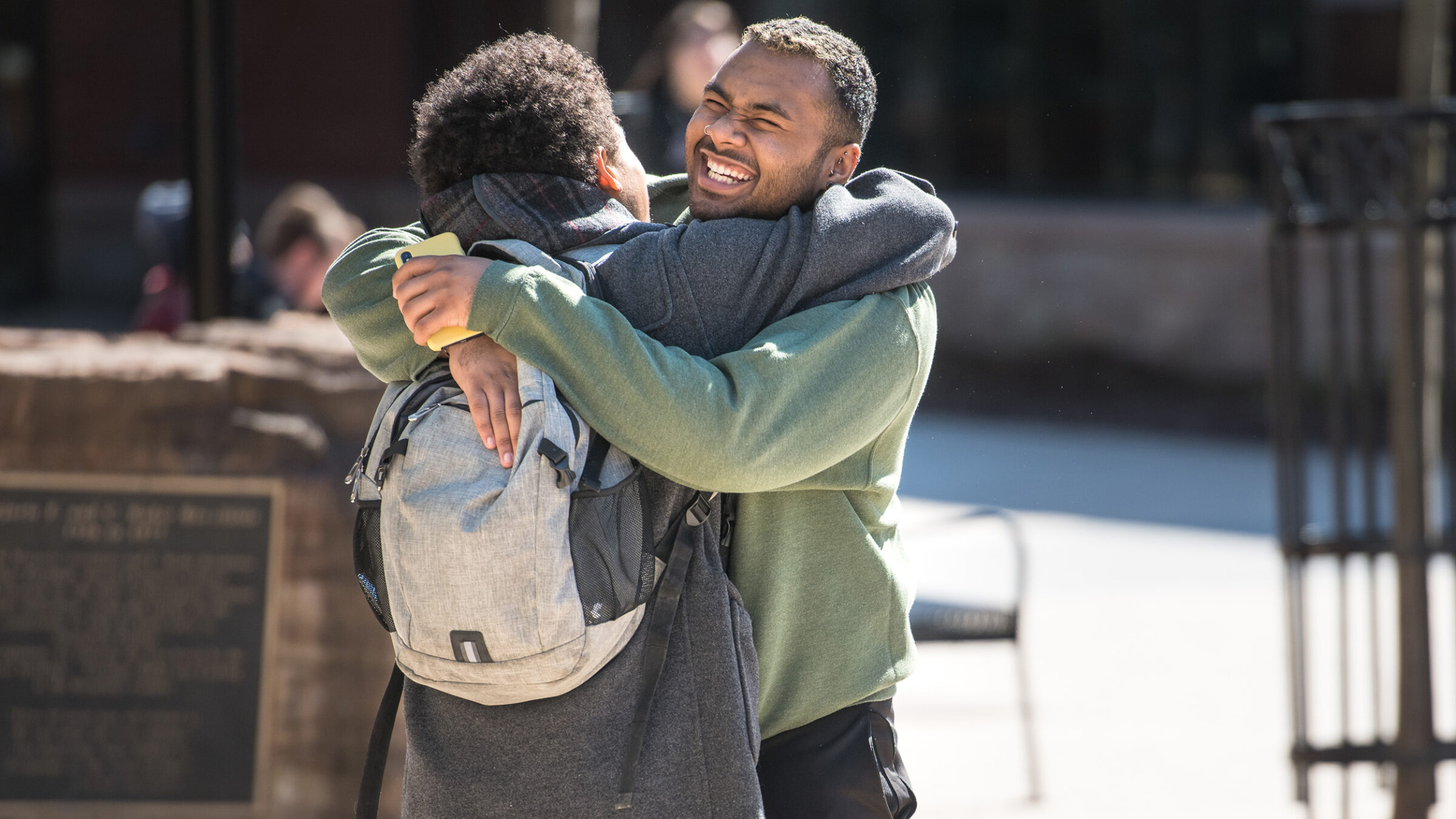 two students hug as a greeting, smiling