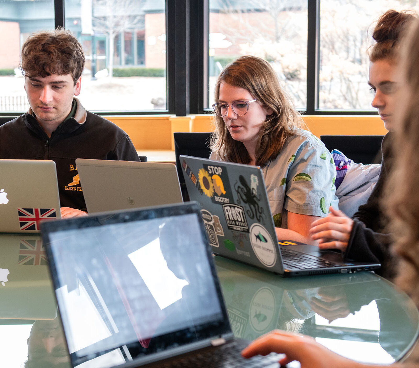 Group of students around a table working on their laptops
