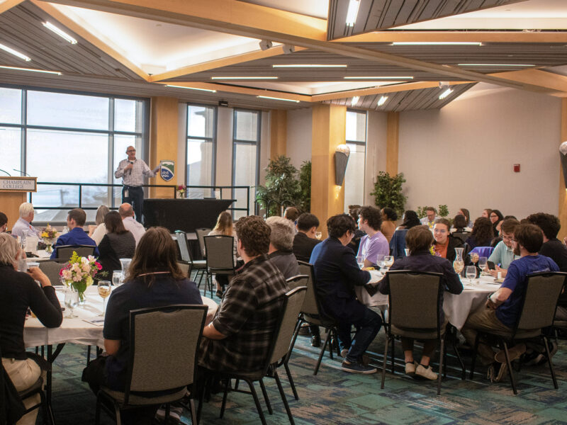 an event in the Champlain Room, people seated around tables, speaker at the head of the room