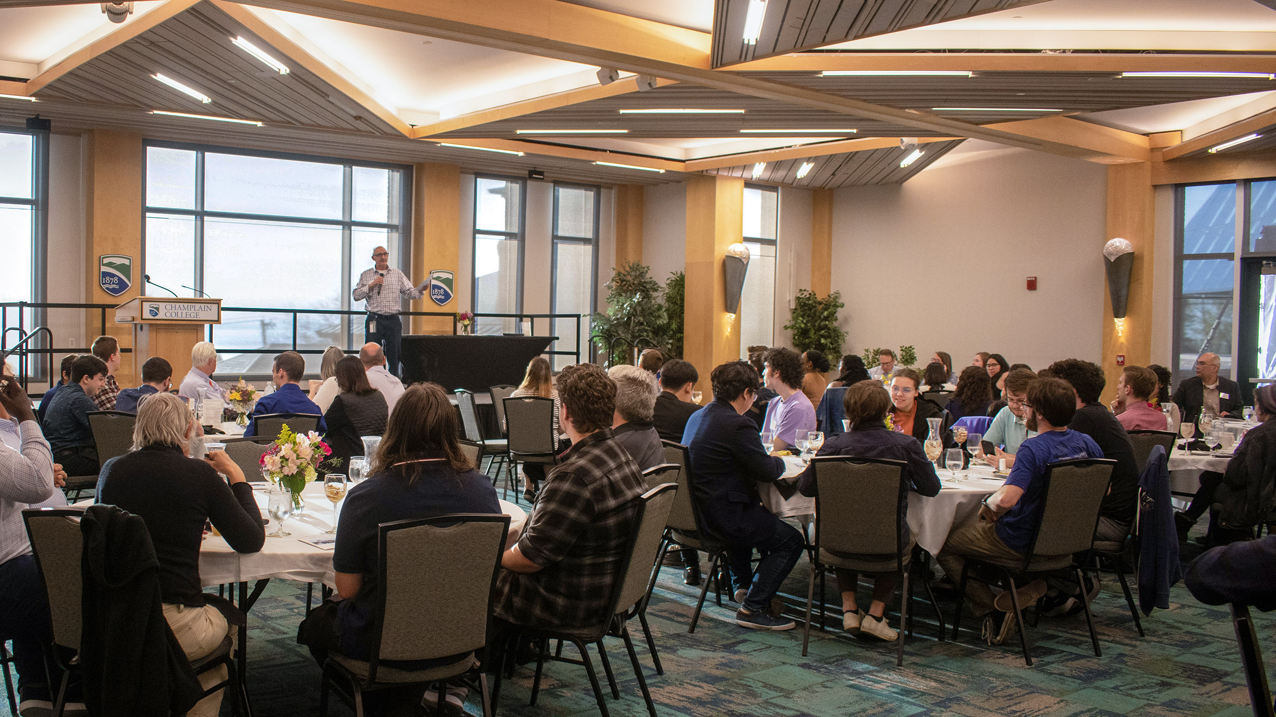 an event in the Champlain Room, people seated around tables, speaker at the head of the room