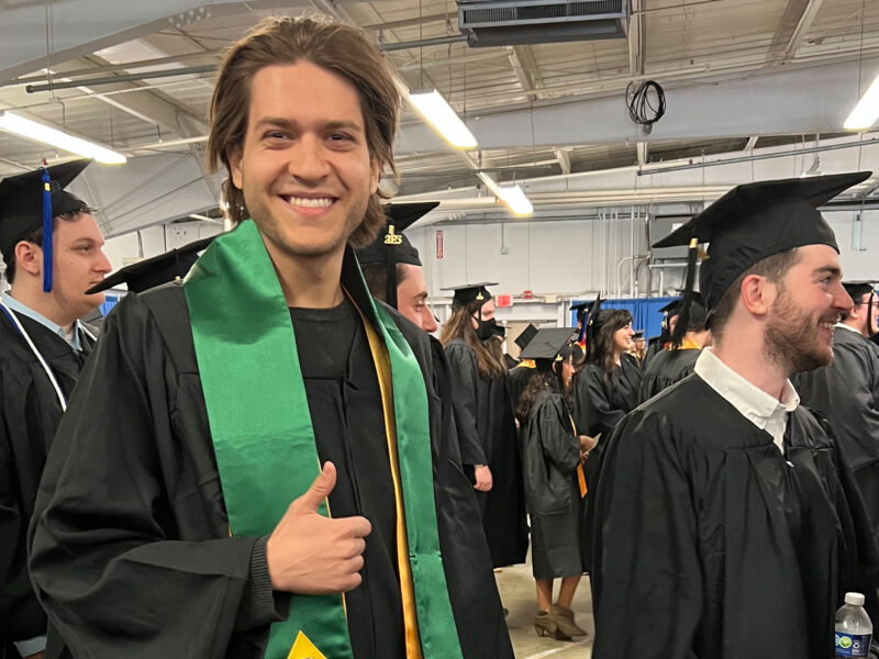 International student from Brazil signing a thumbs up during commencement