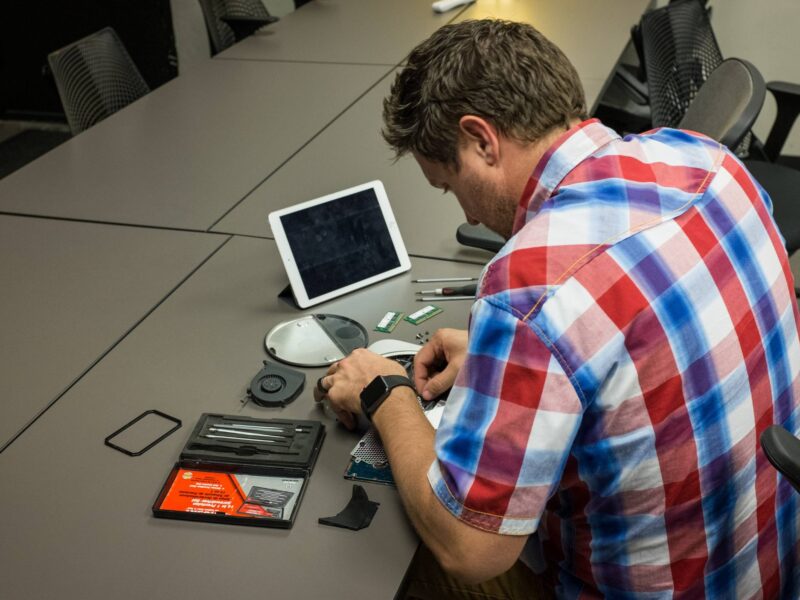 A staff member working on electronics at a table with an IPad