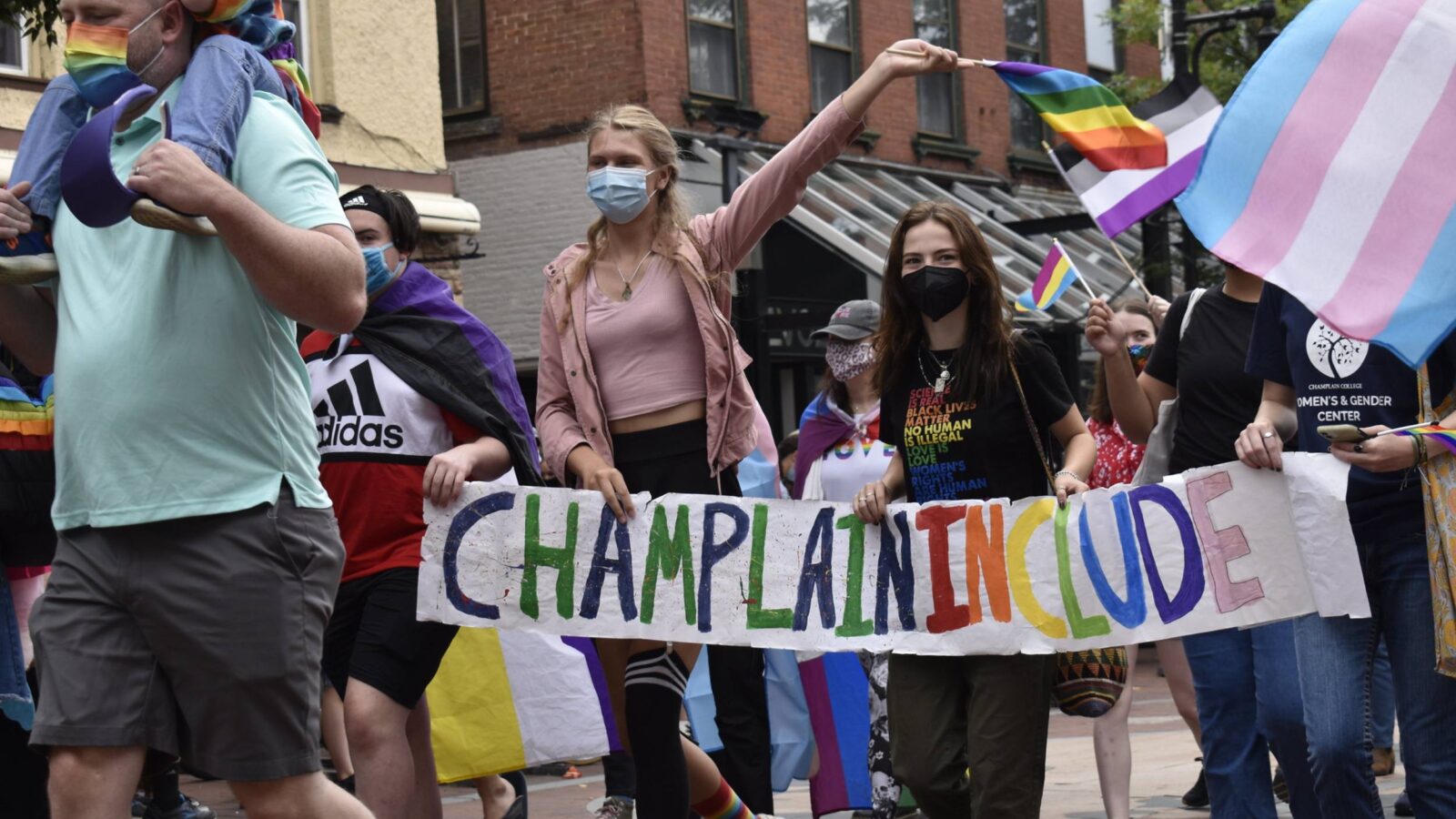 students marching in the pride parade sporting Champlain Include, pride flags, and WGC.