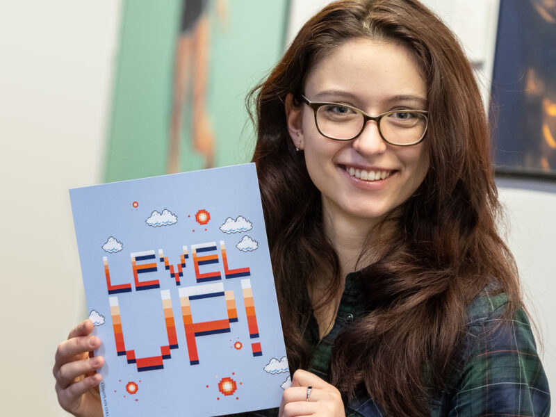 Olga Kachura, International student holding a sign that says "level up!"