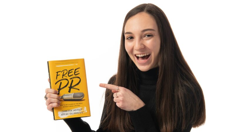 A student headshot smiling and pointing at a book about public relations