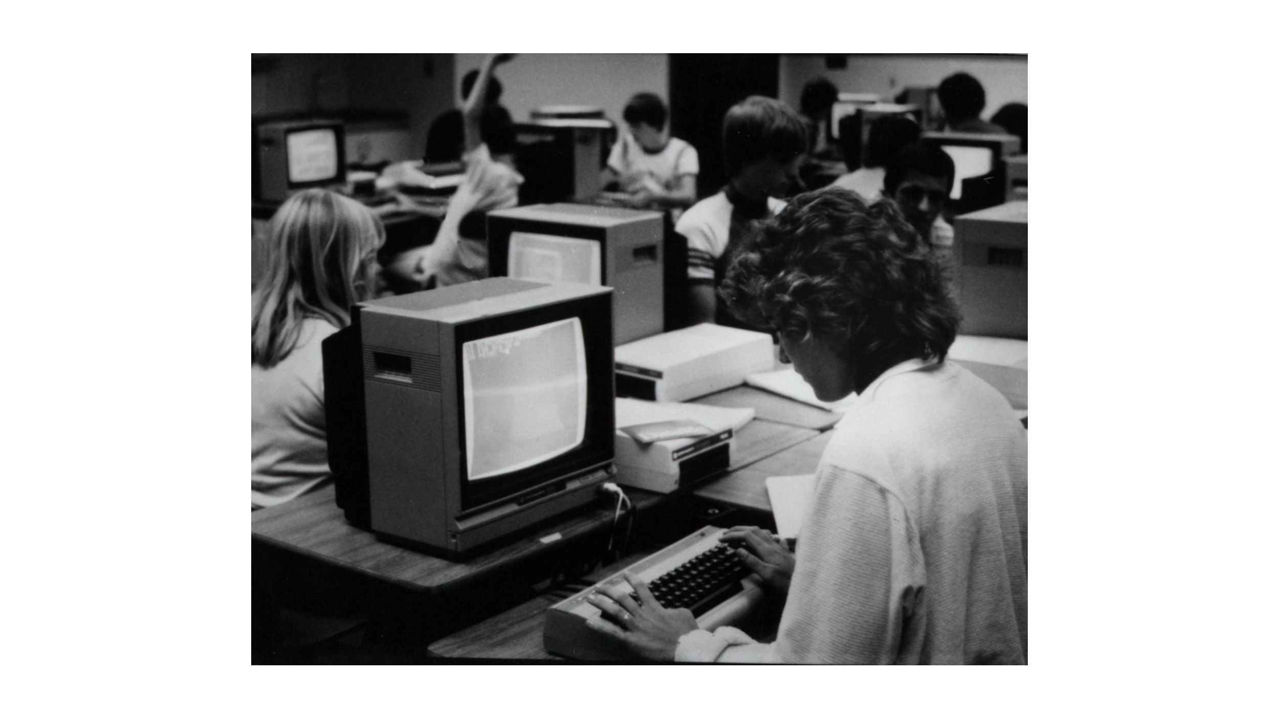 Black and white photograph of a student working at a computer in a Champlain College computer lab.