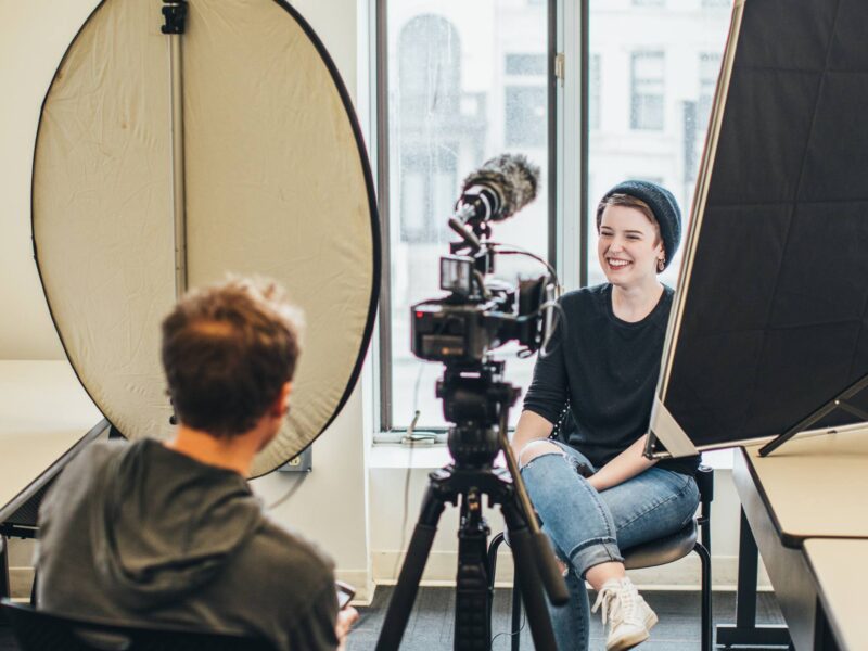 Students filming an interview in a classroom, smiling
